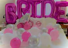 some balloons are laying on a bed with the word bride spelled out in large letters