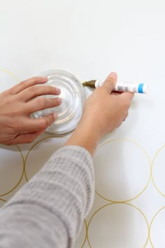 a person is painting a wall with white paint and gold circles on the wall behind them