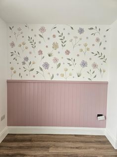 an empty room with pink paneling and flowers painted on the wall behind it,