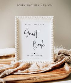 a sign that says guest book sitting on top of a wooden tray next to some blankets