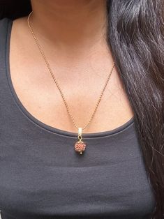 a woman wearing a necklace with a heart shaped pendant hanging from it's side