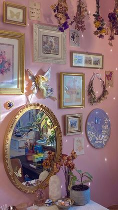 there is a mirror and many pictures on the wall in this room with pink walls