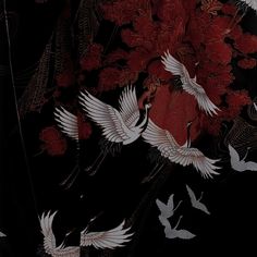 there are many white birds flying in the dark sky with red and black flowers behind them