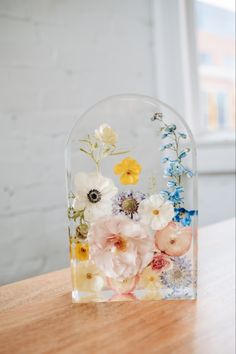 a glass vase filled with flowers on top of a wooden table