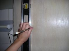 a person holding a pencil in front of a closed door with the handle on it