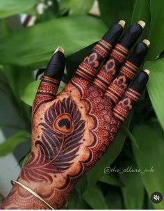 a person's hand with henna tattoos on it and green leaves in the background