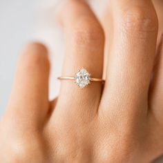 a woman's hand with a diamond ring on top of her finger, showing the center stone