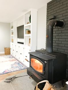 a wood stove sitting in the middle of a living room next to a wall mounted tv