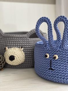 two knitted baskets sitting on top of a table next to each other with faces drawn on them