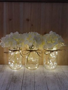 three mason jars with flowers in them sitting on a table