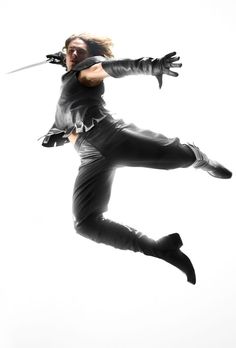 a woman is jumping in the air with two swords