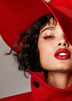 a woman wearing a red hat with her eyes covered by a red coat and lipstick