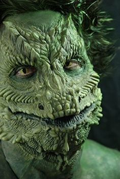 a close up of a person with green hair and monster like makeup on their face