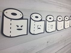 a row of paper towels hanging on a wall with faces drawn on them and eyes drawn in the middle