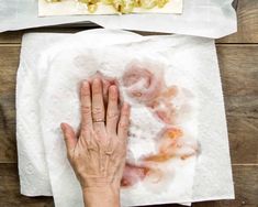 a person is holding their hand up to some food on top of paper towels and napkins