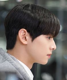 a young man with black hair wearing a grey hoodie and looking off to the side