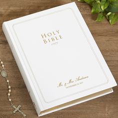 an open bible next to a rosary on a wooden table