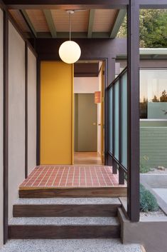 an entry way with steps leading up to the front door and yellow doors on both sides