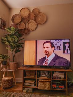 a flat screen tv sitting on top of a wooden stand in a living room next to a potted plant