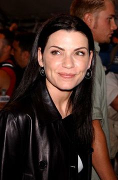 a woman with long black hair wearing a leather jacket and smiling for the camera at an event