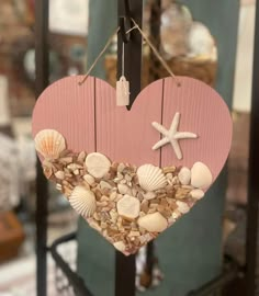 a heart shaped decoration with seashells and starfish hanging from it's side