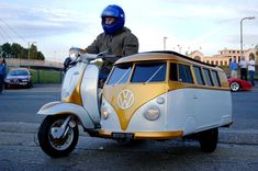 a man riding on the back of a white and yellow vw bus with dogs in it