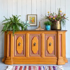 a wooden cabinet with flowers and plants on top