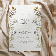 a wedding card with flowers on it sitting on top of a bed covered in white linen