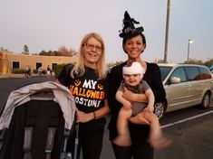 two women and a baby are standing in a parking lot