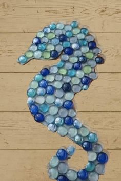 a seahorse made out of glass beads sitting on top of a wooden floor next to a wall