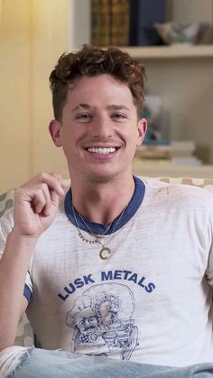 a man sitting on top of a couch wearing a shirt that says luck metals