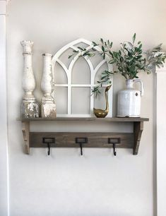 a shelf that has some vases on top of it and two plants in the middle