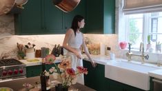 a woman standing in a kitchen next to a sink