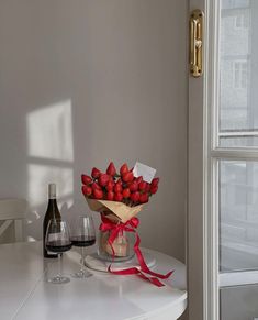 a bouquet of strawberries on a table next to a bottle of wine