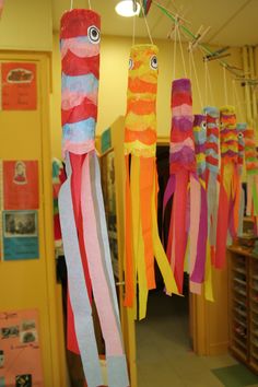 colorful paper streamers hanging from the ceiling in a room with pictures on the walls