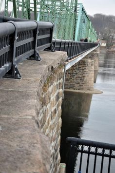 a bridge that is over water with people walking on the side and one person standing on the other side