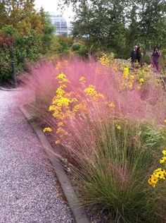 people are walking through the park by some flowers