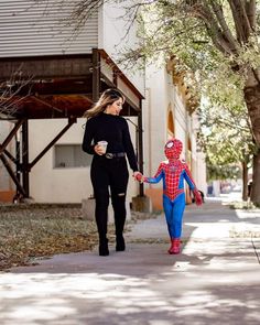 a woman walking down a sidewalk holding hands with a spider man