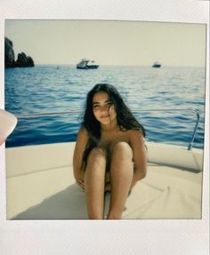 a naked woman sitting on the back of a boat