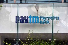 the sign for raytm payments bank is displayed in front of a glass building with trees and bushes around it