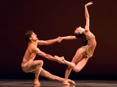 two dancers performing on stage with one holding the other's leg