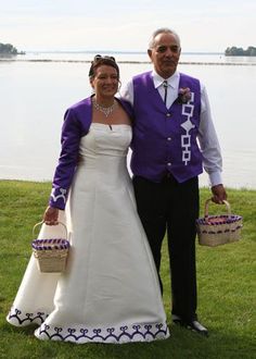 a man and woman dressed in wedding attire standing next to each other on the grass