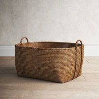 an empty basket sitting on the floor in front of a white wall and wooden floors