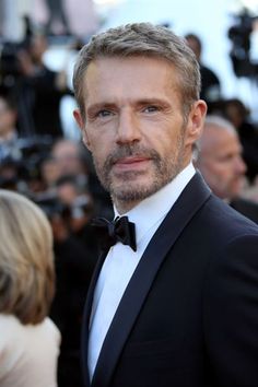 a man in a tuxedo and bow tie posing for the camera at an event