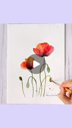 someone is painting flowers with watercolors on paper