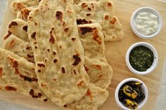 some pita breads and dipping sauce on a cutting board