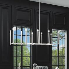 a kitchen with black cabinets and white counter tops is pictured in this image, there are candles hanging from the chandelier