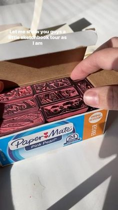 someone is opening up a box with paper mate on the outside and inside, while another person's hand reaches for it