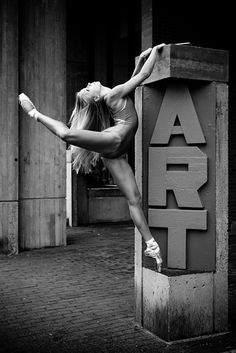 black and white photograph of a ballerina doing a split in front of the art sign