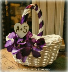 a white basket with purple flowers in it and a sign that says a + s